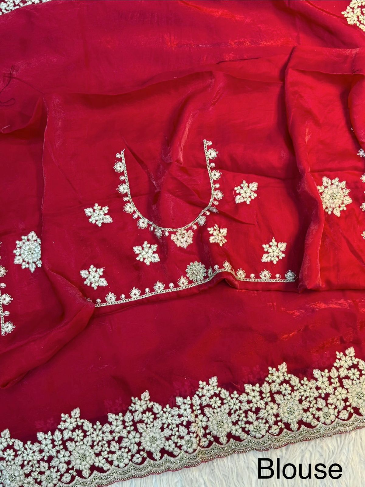 A bridal red Fandy silk saree enriched with heavy floral embroidery in white threadwork and stone detailing. The coordinated blouse adds a regal touch, perfect for weddings and grand occasions.