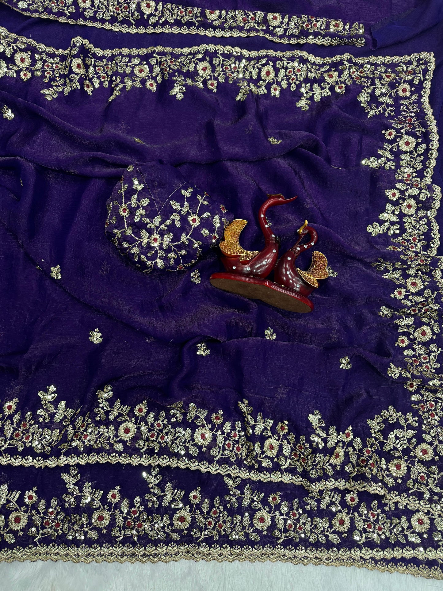 A deep purple Fandy silk saree adorned with heavy golden zari embroidery and sequin detailing. The ornate floral border and matching blouse piece add sophistication and grandeur, perfect for festive and wedding occasions.