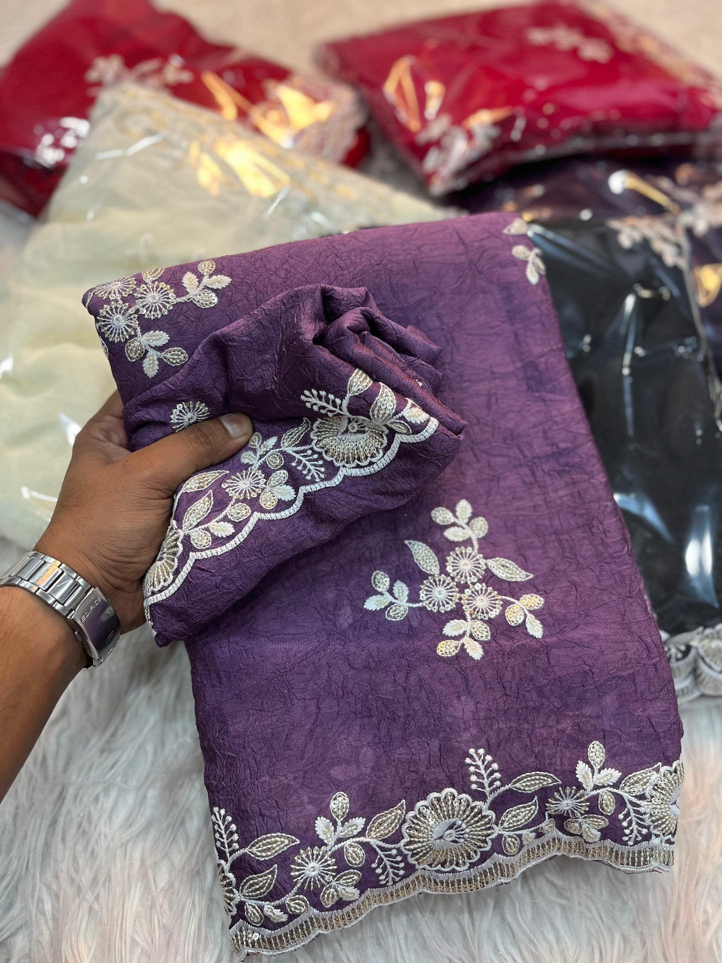 A lilac-toned purple saree featuring subtle floral embroidery and intricate lace border detailing. Displayed with a matching blouse piece, this saree offers a refined balance of tradition and modern grace.