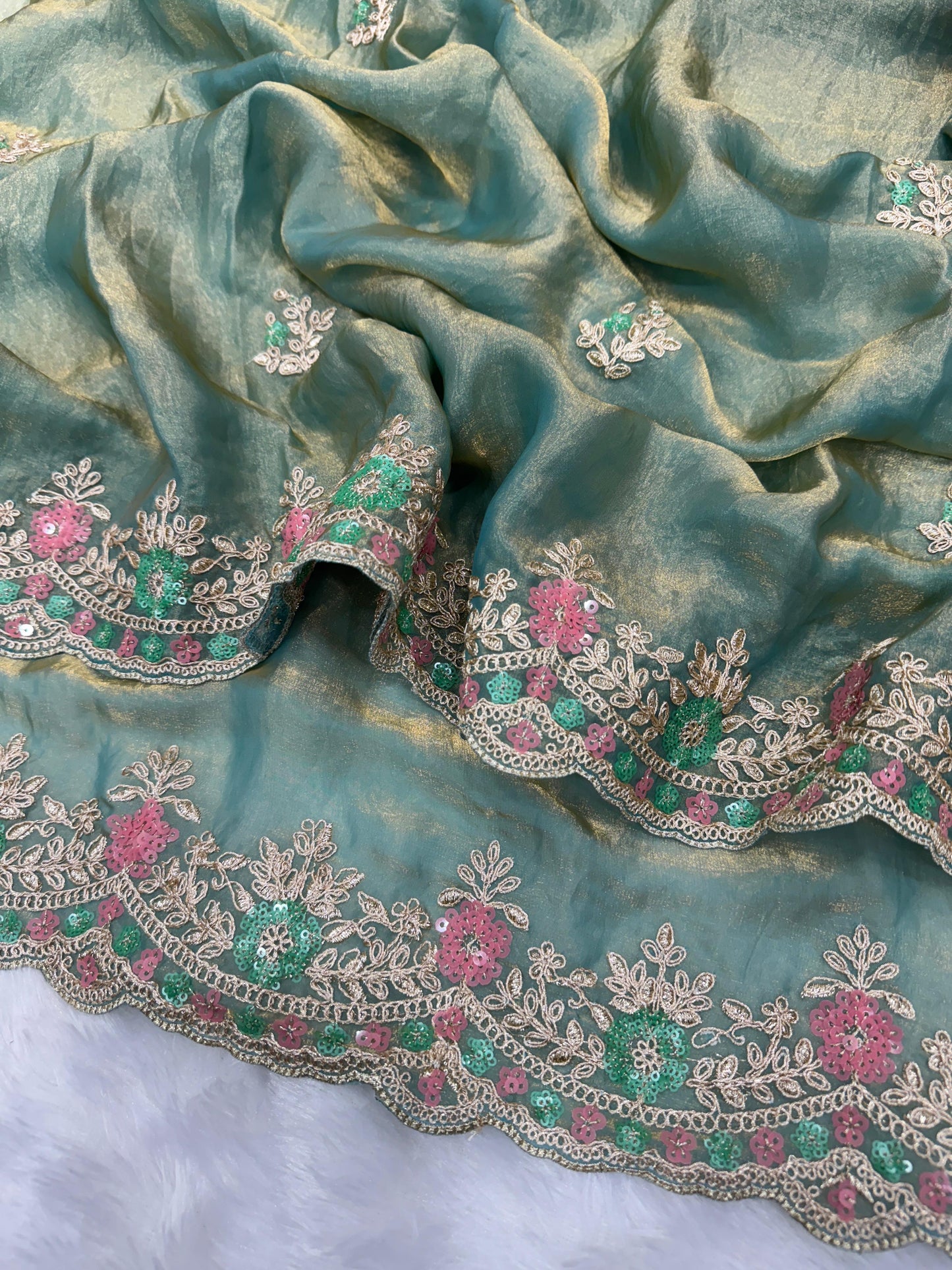 A woman dressed in a pastel blue space silk saree adorned with sequin floral embroidery. The saree is paired with a matching blouse and pearl choker, creating a sophisticated and romantic look perfect for festive occasions.