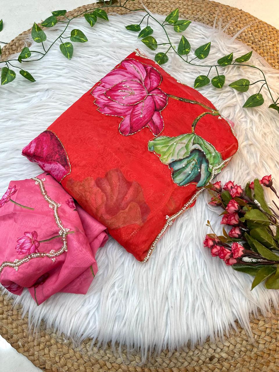 A festive organza saree showcasing a red-to-pink gradient, adorned with artistic lotus designs and finished with a pearl scalloped border. Comes with a matching lotus-embroidered blouse for a graceful ensemble.