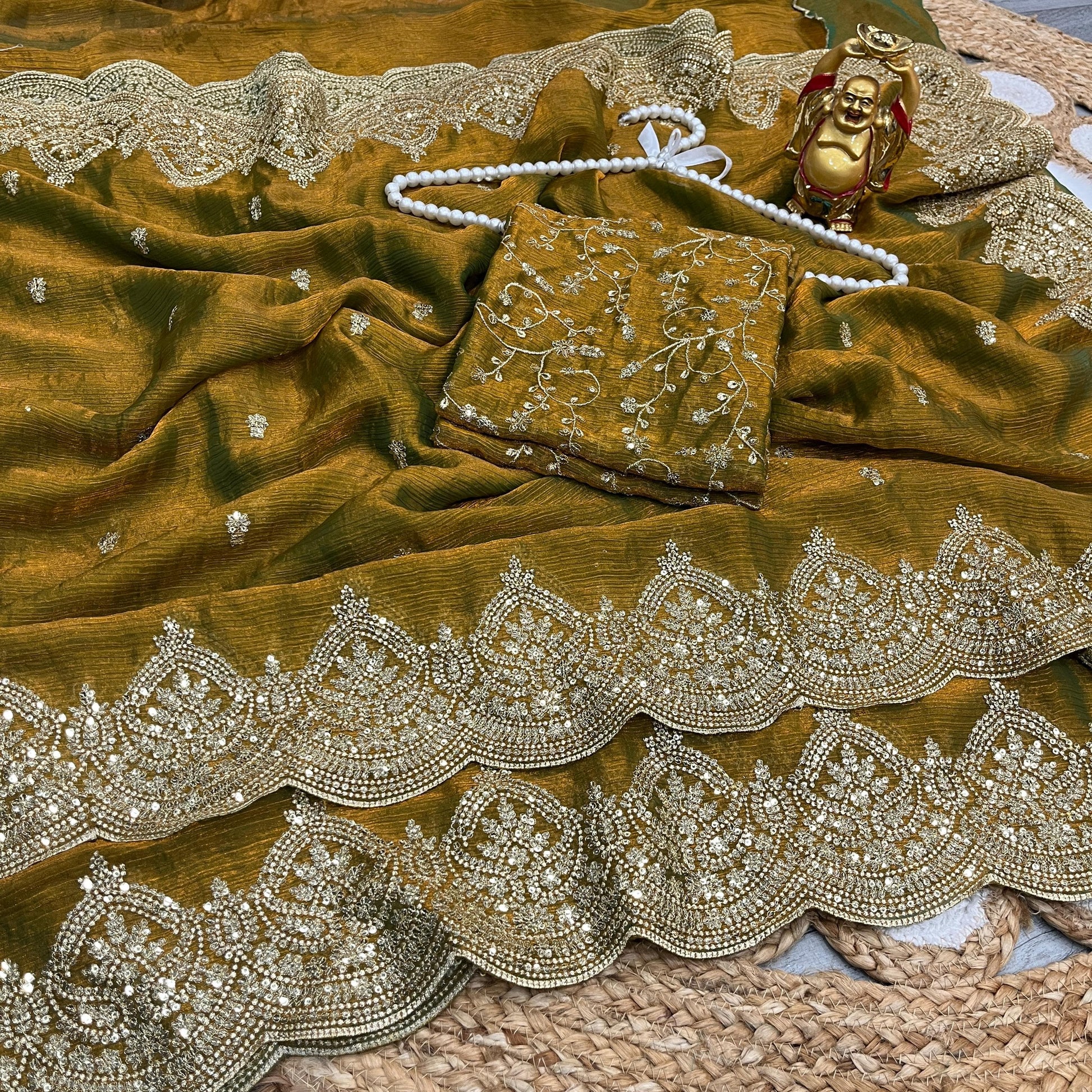 A stunning antique mustard saree featuring detailed zari embroidery and shimmering sequin embellishments along a scalloped golden border. The matching blouse piece adds to the saree’s grand and traditional elegance.