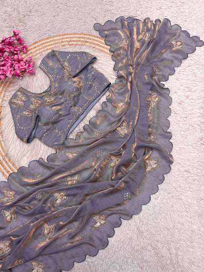 An ash grey space silk saree featuring golden and silver embroidered butterfly motifs across the fabric. The saree comes with a stitched blouse embellished with circular embroidery, radiating timeless sophistication.