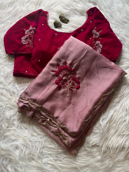 A luxurious Rangoli silk saree in blush pink, highlighted with elegant floral embroidery and a shimmery gold border. The ensemble is paired with a richly embroidered maroon velvet blouse, creating a sophisticated bridal or festive look.