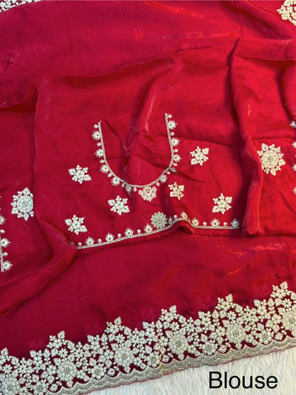 A bridal red Fandy silk saree enriched with heavy floral embroidery in white threadwork and stone detailing. The coordinated blouse adds a regal touch, perfect for weddings and grand occasions.