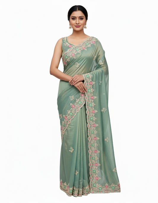 A graceful woman wearing a celestial blue space silk saree with intricate floral embroidery along the border. The soft silk fabric glows under natural light, complemented by a matching blouse and pearl accessories.