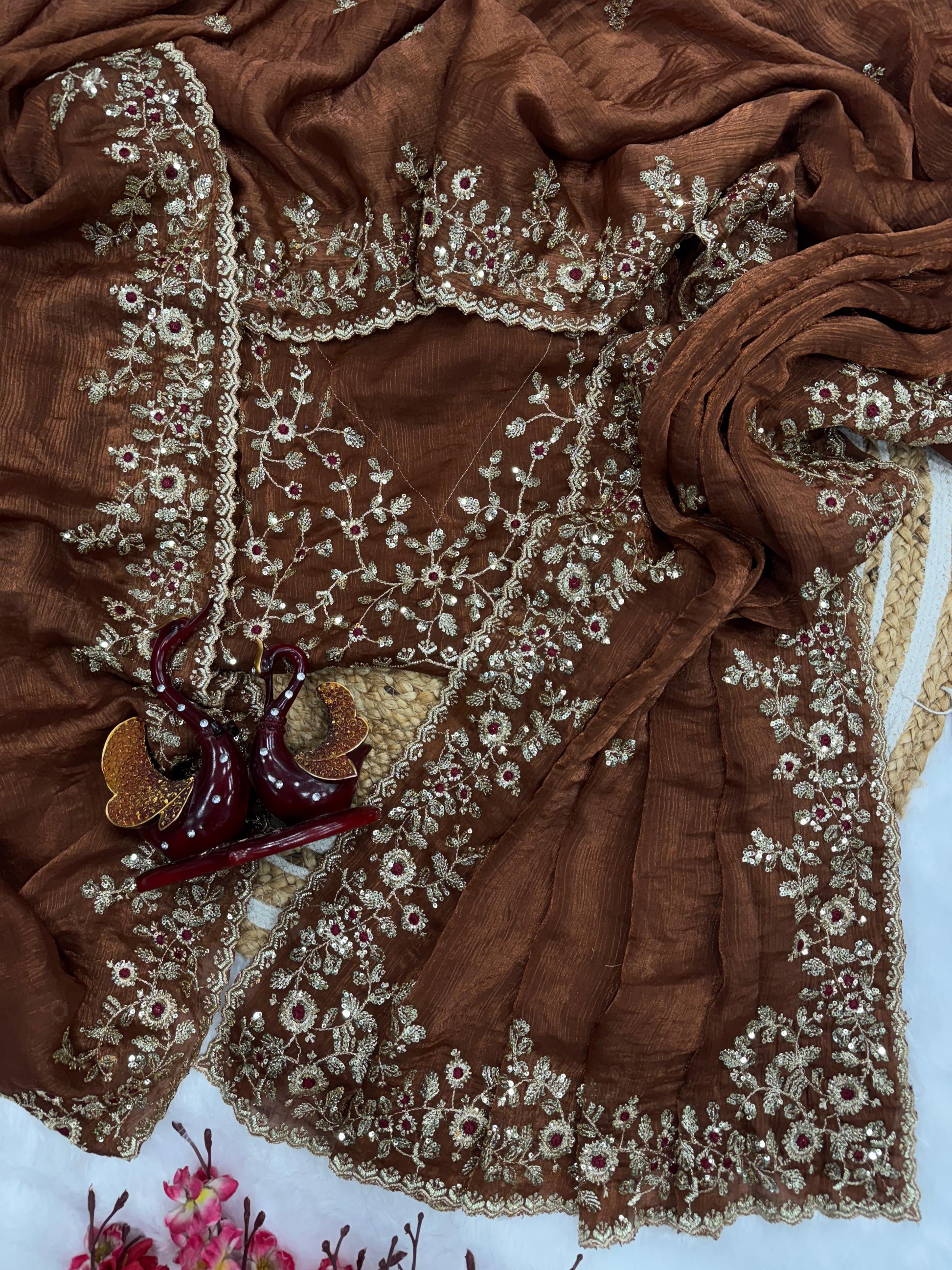 A coffee brown Fandy silk saree showcasing exquisite hand-embroidered floral patterns in golden and maroon threads. The scalloped border and fine detailing give it a rich, traditional bridal appeal.