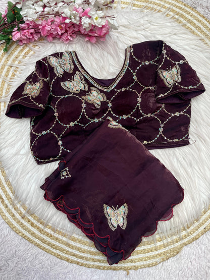 A luxurious maroon space silk saree beautifully detailed with shimmering butterfly embroidery and a scalloped edge. The outfit includes a stitched blouse with matching embroidery and geometric sequin work, ideal for weddings and parties.