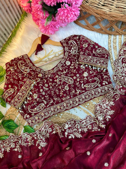 A premium maroon space silk saree featuring elegant hand embroidery with fine golden zari motifs and a scalloped border. The matching embroidered blouse enhances the saree’s regal and sophisticated look.