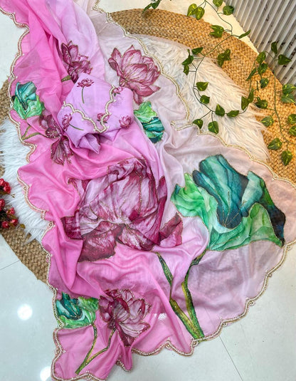 A designer soft organza saree adorned with watercolor-style lotus flowers in vibrant pink and green tones. The scalloped pearl border and matching floral blouse add sophistication and beauty to this graceful ensemble.