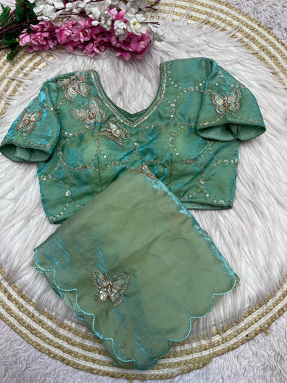 A luxurious pista space silk saree embellished with shimmering butterfly motifs and a scalloped border. The matching stitched blouse, decorated with circular sequin embroidery, adds a graceful festive charm to the outfit.