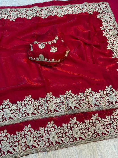 A designer red Fandy silk saree beautifully embellished with handcrafted white floral embroidery on the border. The matching blouse enhances the luxurious and sophisticated appeal of this festive ensemble.