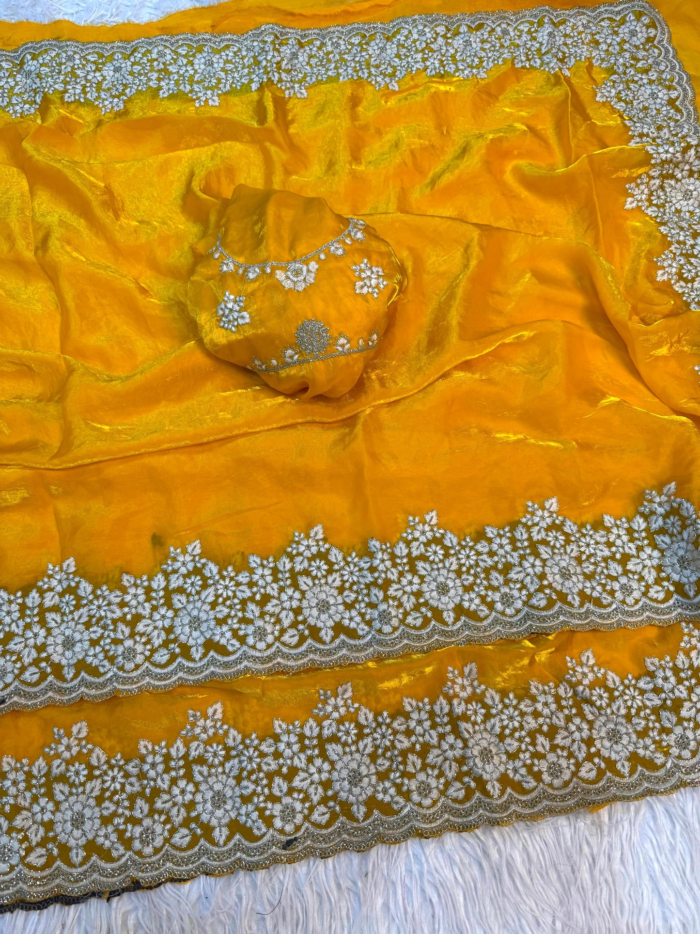 A designer yellow Fandy silk saree beautifully embellished with handcrafted white floral embroidery on the border. The blouse matches the saree with coordinated embroidery, perfect for festive and ceremonial occasions.