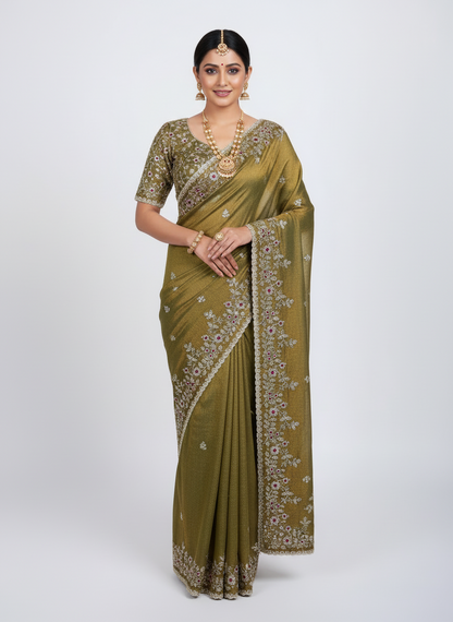 A rich golden Fandy silk saree beautifully embellished with intricate floral embroidery in gold and maroon threads. The saree features a detailed scalloped border and matching blouse piece, displayed with elegant decor, exuding a luxurious and royal charm.