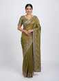 A rich golden Fandy silk saree beautifully embellished with intricate floral embroidery in gold and maroon threads. The saree features a detailed scalloped border and matching blouse piece, displayed with elegant decor, exuding a luxurious and royal charm.