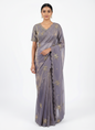 A beautiful grey space silk saree embellished with delicate golden bird embroidery and scalloped edges. The saree comes with a matching stitched blouse intricately adorned with zari and sequin work, creating an elegant and festive look.