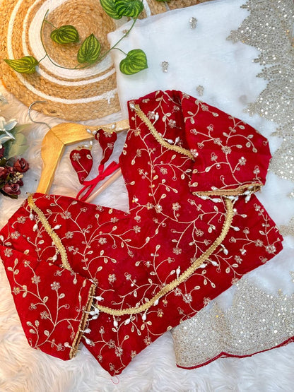 An ivory white saree featuring golden sequin embroidery and a scalloped border with red piping. Paired with a richly embroidered red blouse, the look blends elegance and sophistication, perfect for weddings or festive occasions.