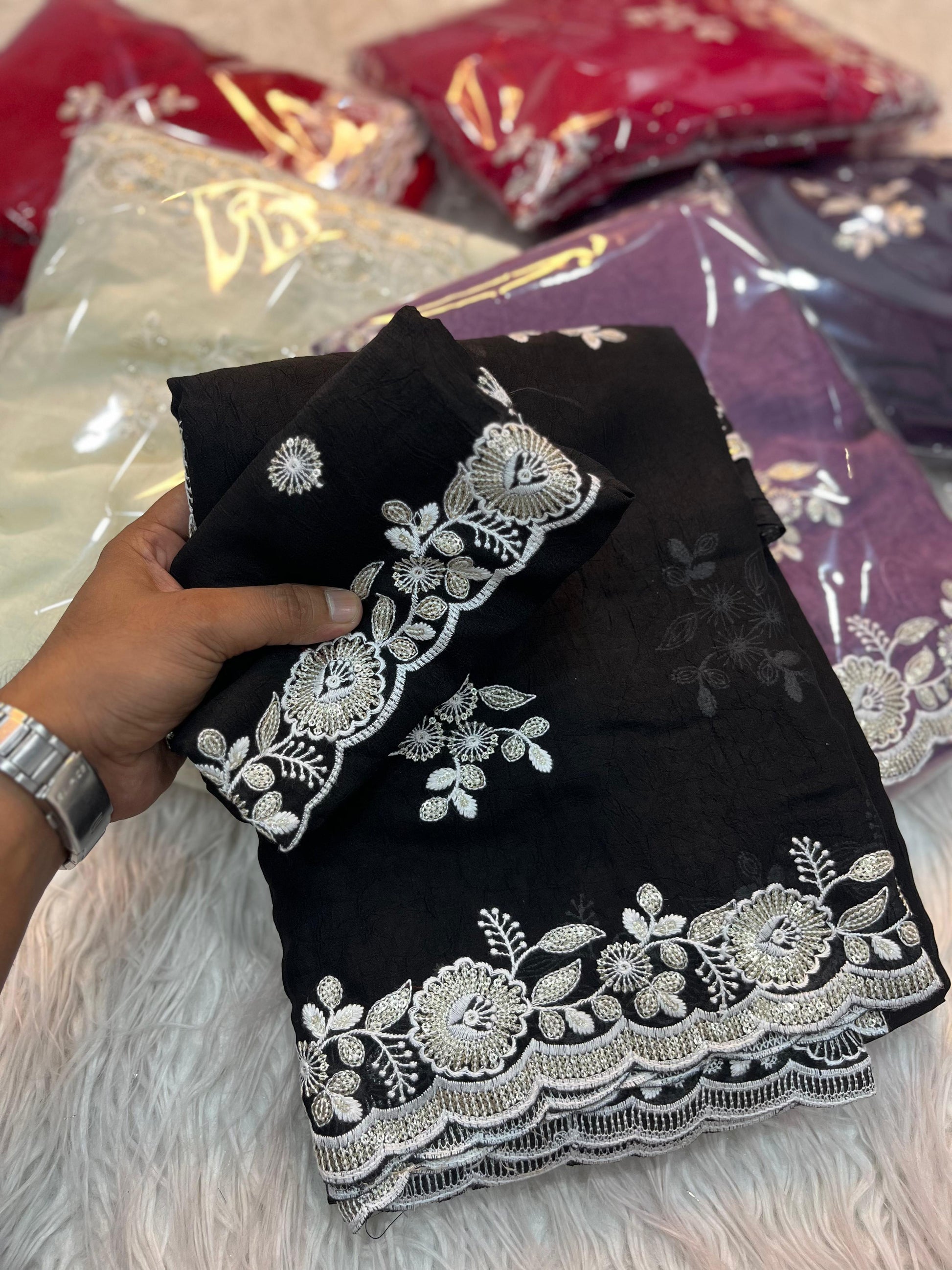 A jet-black designer saree adorned with silver thread floral embroidery and sequin detailing. The saree’s scalloped border and matching blouse piece add a touch of sophistication, making it perfect for evening wear and festive occasions.