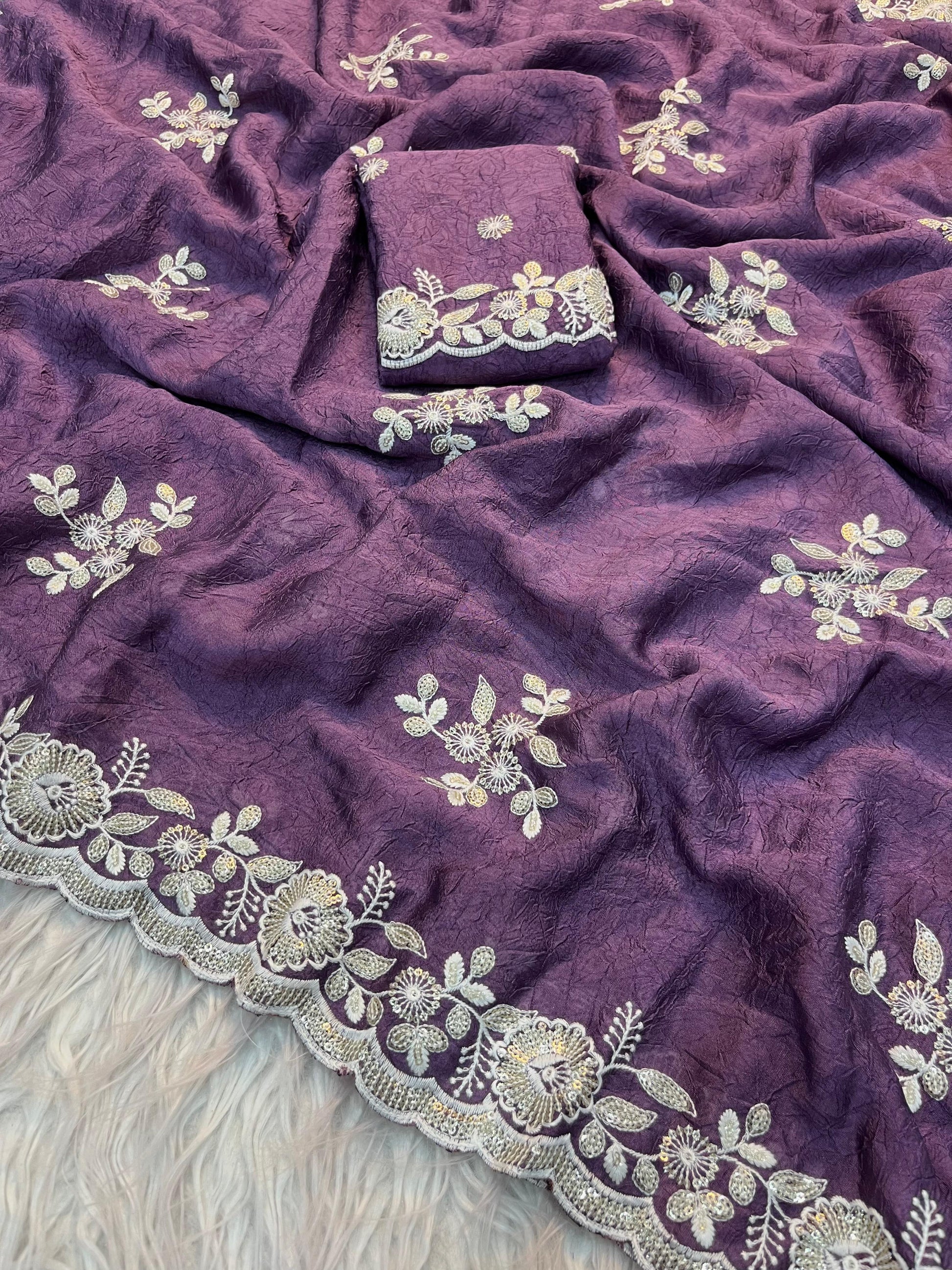 A luxurious violet saree with fine zari and thread floral embroidery, highlighted by a beautifully scalloped edge. The set includes a matching blouse piece, making it a perfect choice for weddings and special occasions.
