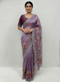 A stunning onion-colored organza saree adorned with intricate multicolor floral embroidery along the border. The saree comes with a matching stitched blouse featuring the same vibrant threadwork, combining modern charm with ethnic elegance.