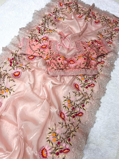 A pastel peach embroidered saree embellished with multicolor thread floral motifs and a detailed embroidered border. The ready blouse enhances the soft and elegant aesthetic, ideal for weddings, parties, and festive gatherings.
