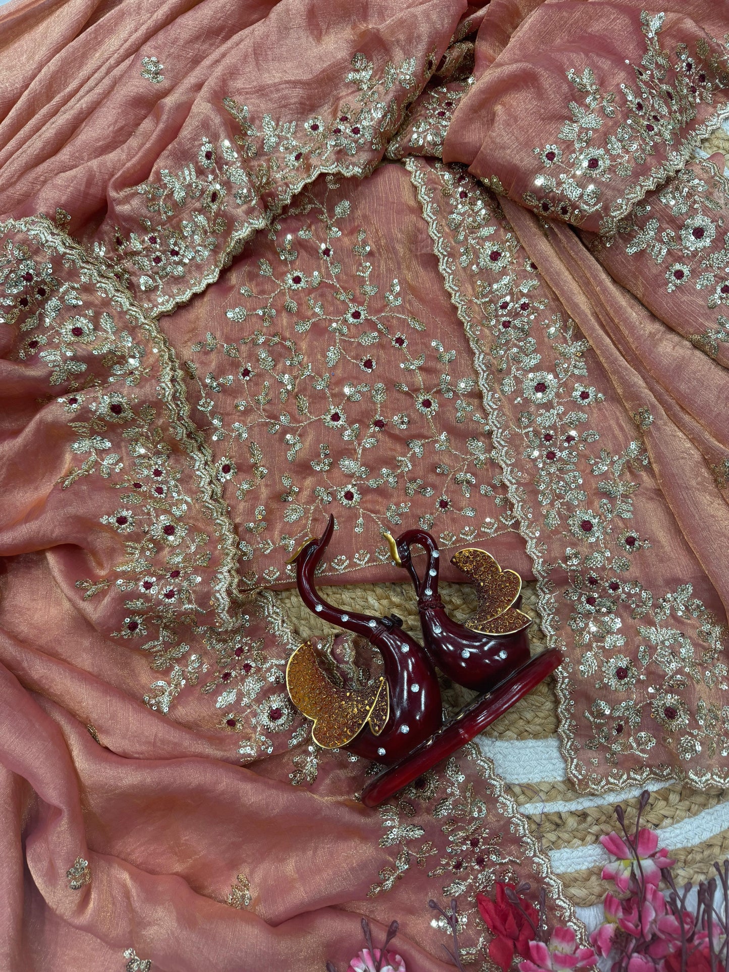 A pastel peach Fandy silk saree featuring delicate golden sequin embroidery and an ornate floral border. The saree comes with a matching embroidered blouse piece, offering a refined and graceful look for special events.