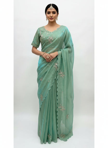 A stunning pista green space silk saree embellished with silver embroidered bird motifs and scalloped edges. The saree is paired with a matching stitched blouse adorned with intricate sequin and zari embroidery, creating a graceful and festive ethnic look.