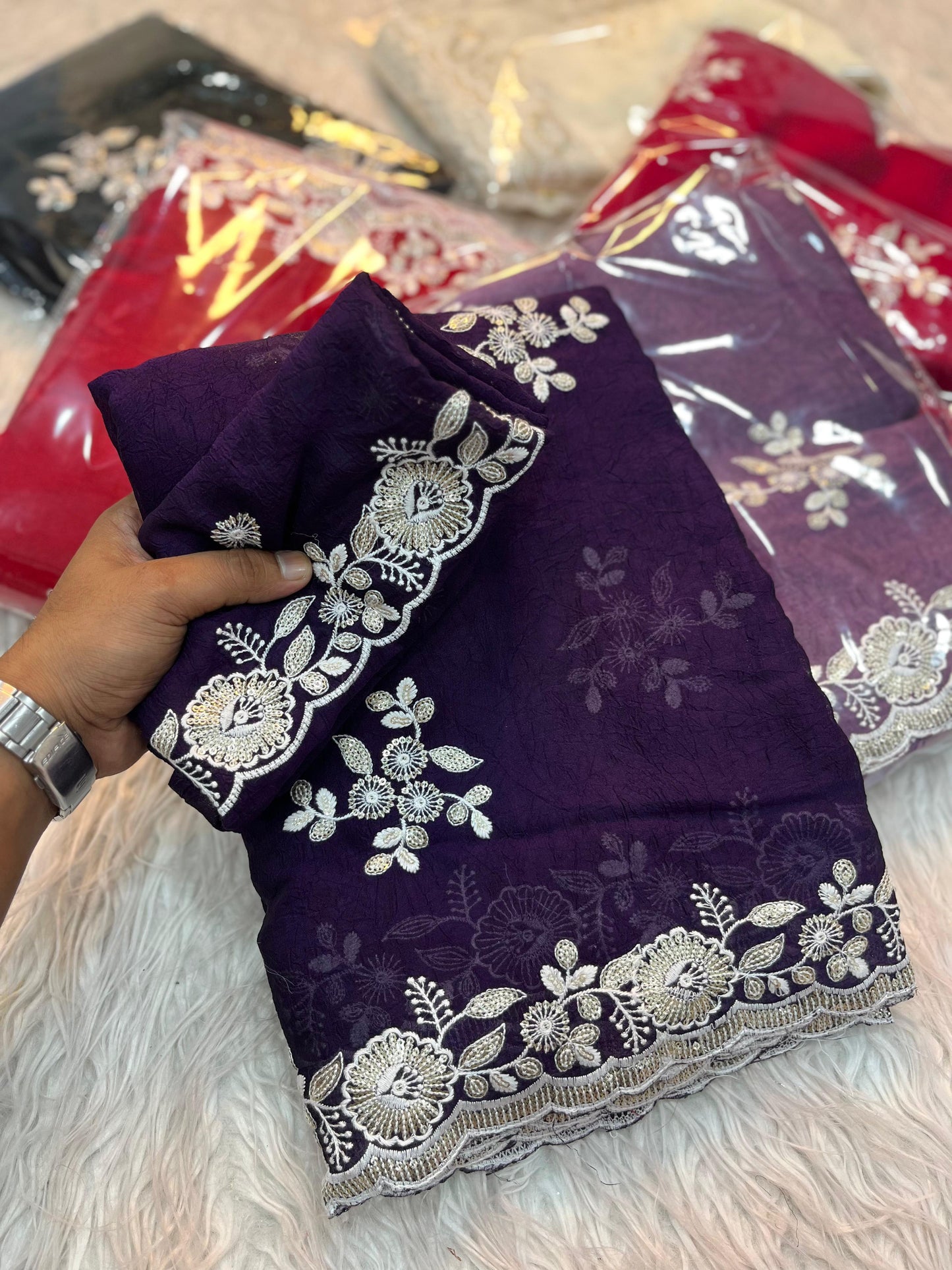 A rich plum purple saree beautifully crafted with silver zari embroidery and delicate floral motifs. The ensemble includes a coordinating blouse with embellished sleeves, offering a regal and sophisticated traditional appeal.
