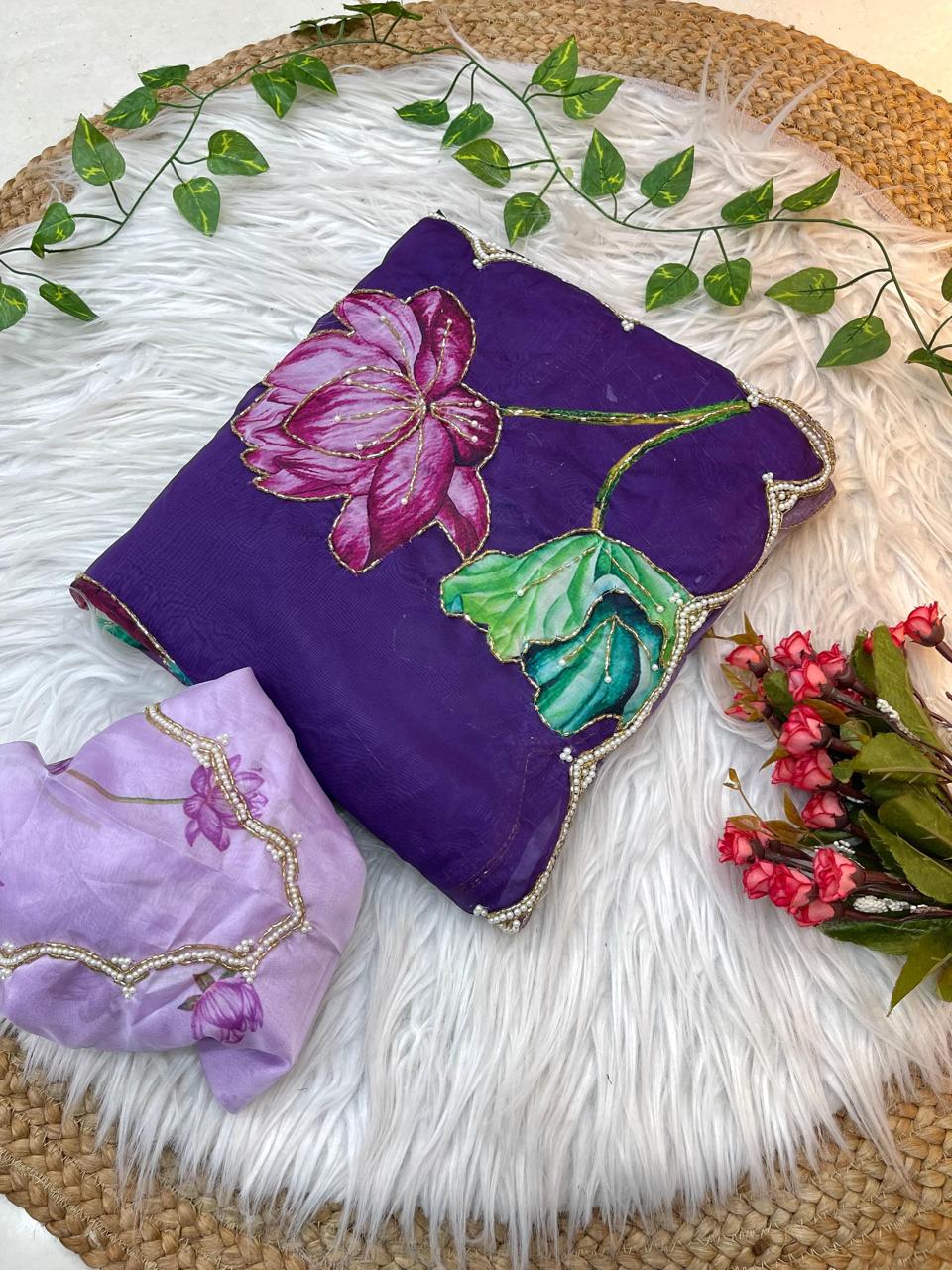 A premium soft organza saree featuring dramatic lotus-print artwork in shades of pink, green, cream, and purple. The pearl-embellished scalloped edging and matching blouse create a luxurious and eye-catching ensemble.