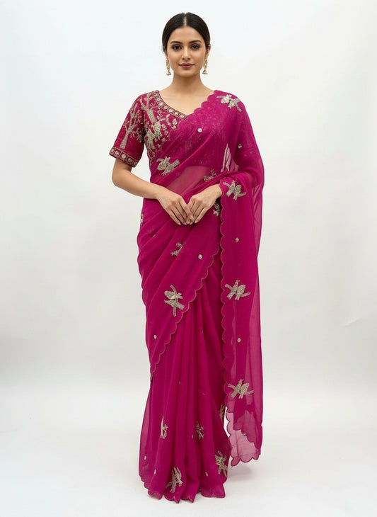 A stunning Rani pink space silk saree embellished with intricate silver bird embroidery and delicate scalloped edges. The saree is paired with a matching heavily embroidered stitched blouse, creating a rich and festive look perfect for special occasions.