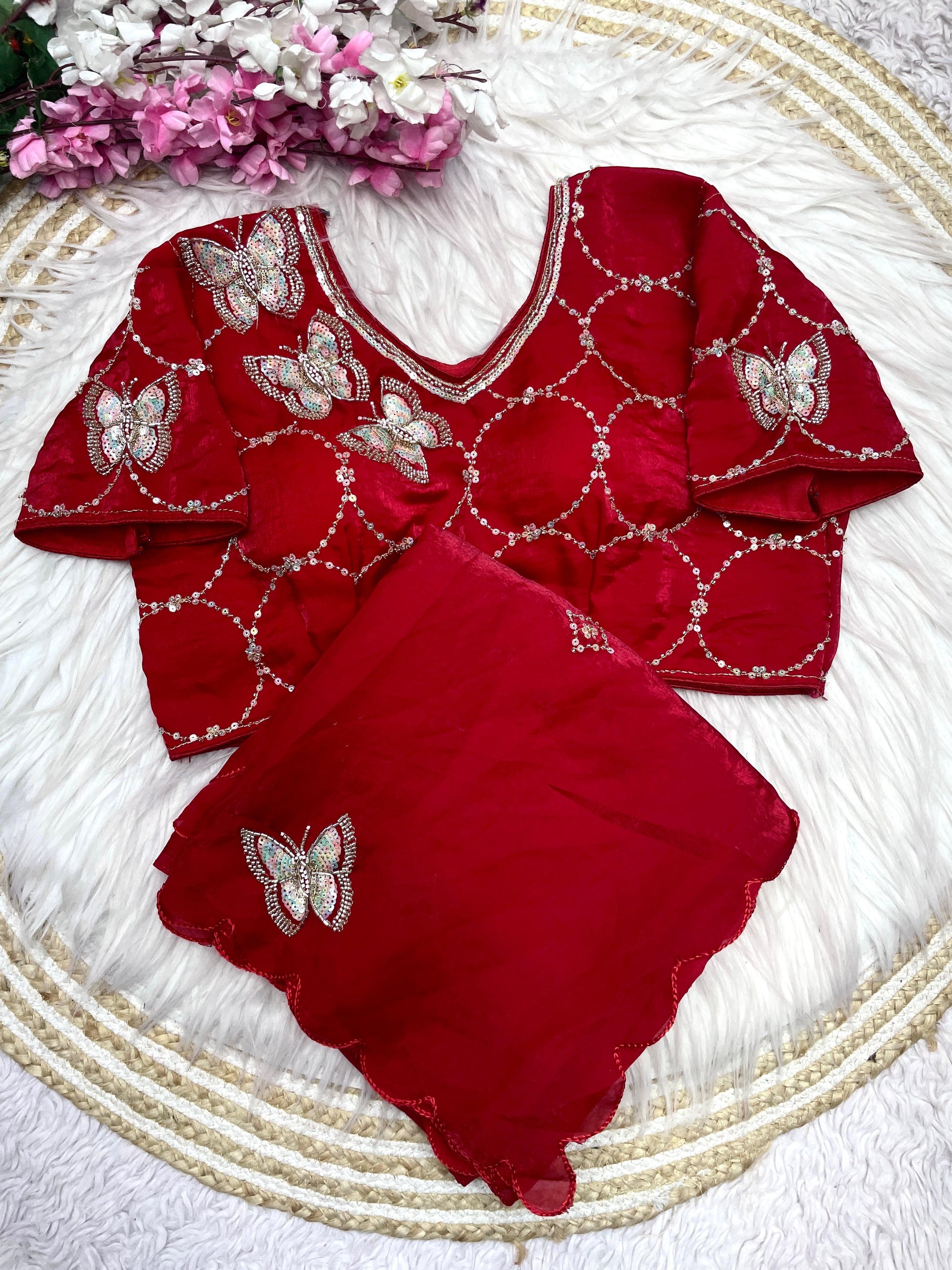 A rich red space silk saree embellished with butterfly-inspired embroidery and delicate sequin detailing. The outfit comes with a matching embroidered blouse, creating a timeless and elegant ethnic look.