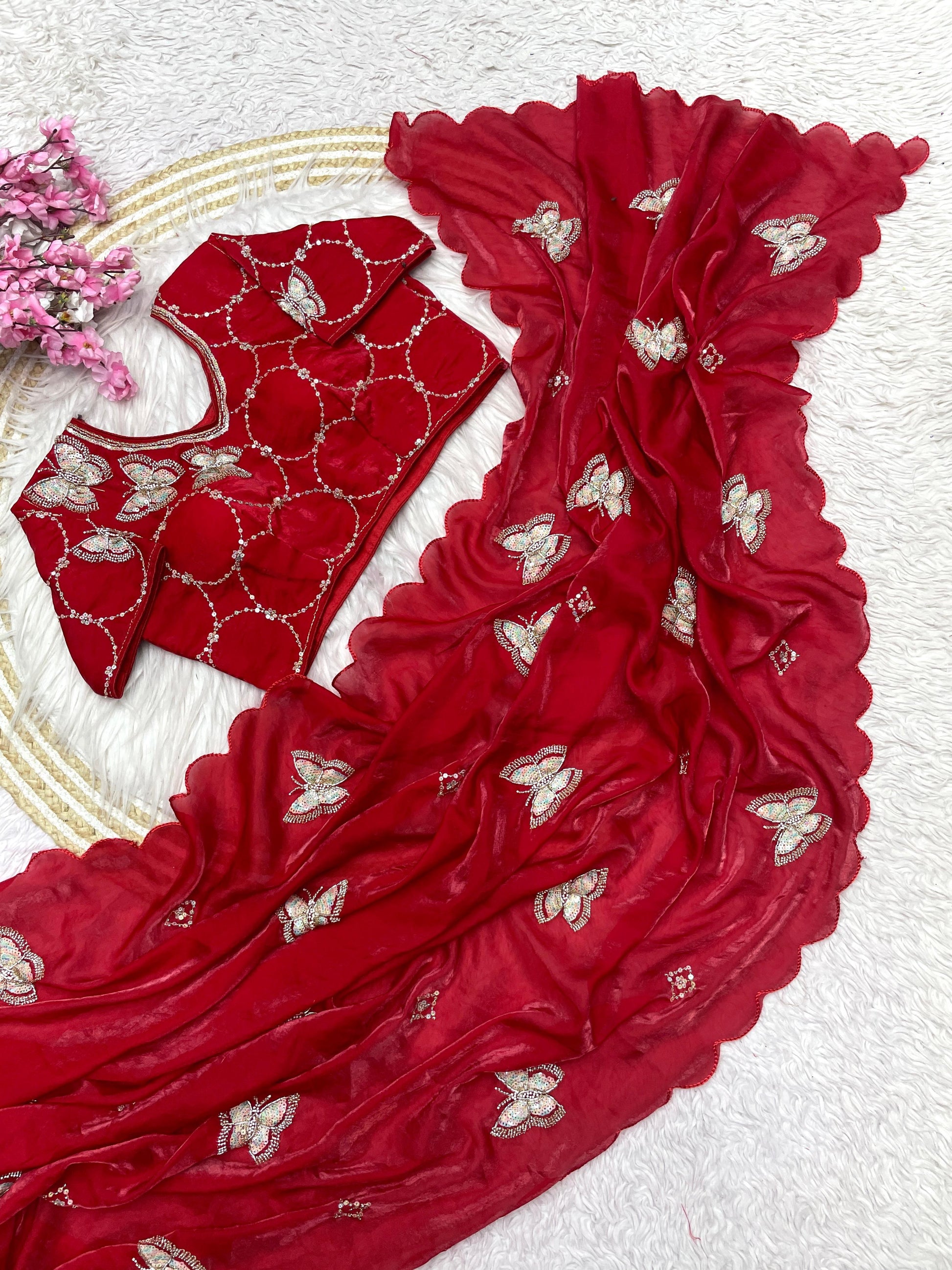 A modern red silk saree adorned with sequin butterfly embroidery and a wavy scalloped edge. The ready-to-wear blouse features matching embroidery, making this outfit a stylish choice for celebrations and parties.