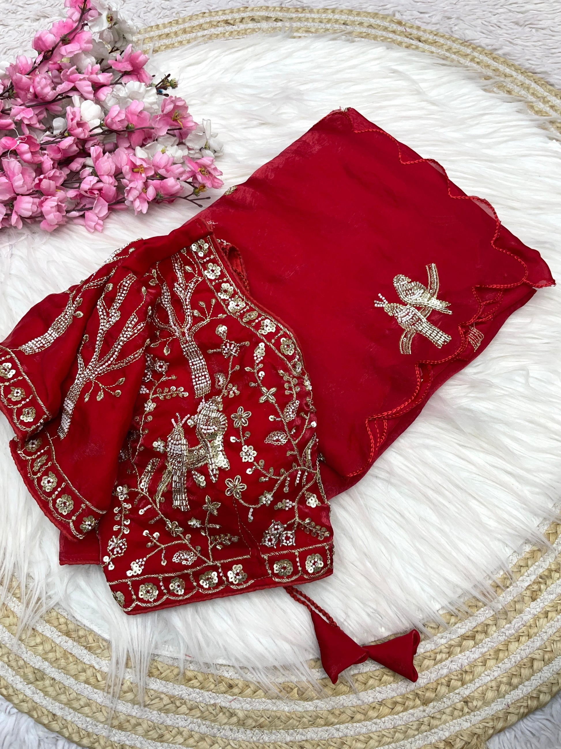 A luxurious red space silk saree adorned with golden and silver bird motifs and delicate scalloped edges. The ensemble includes a matching stitched blouse with intricate embroidery, perfect for weddings and special occasions.