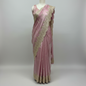 A rose gold saree featuring detailed zari and sequin floral embroidery along a scalloped border. The matching blouse piece adds elegance, making this saree a perfect choice for weddings, receptions, and festive occasions.