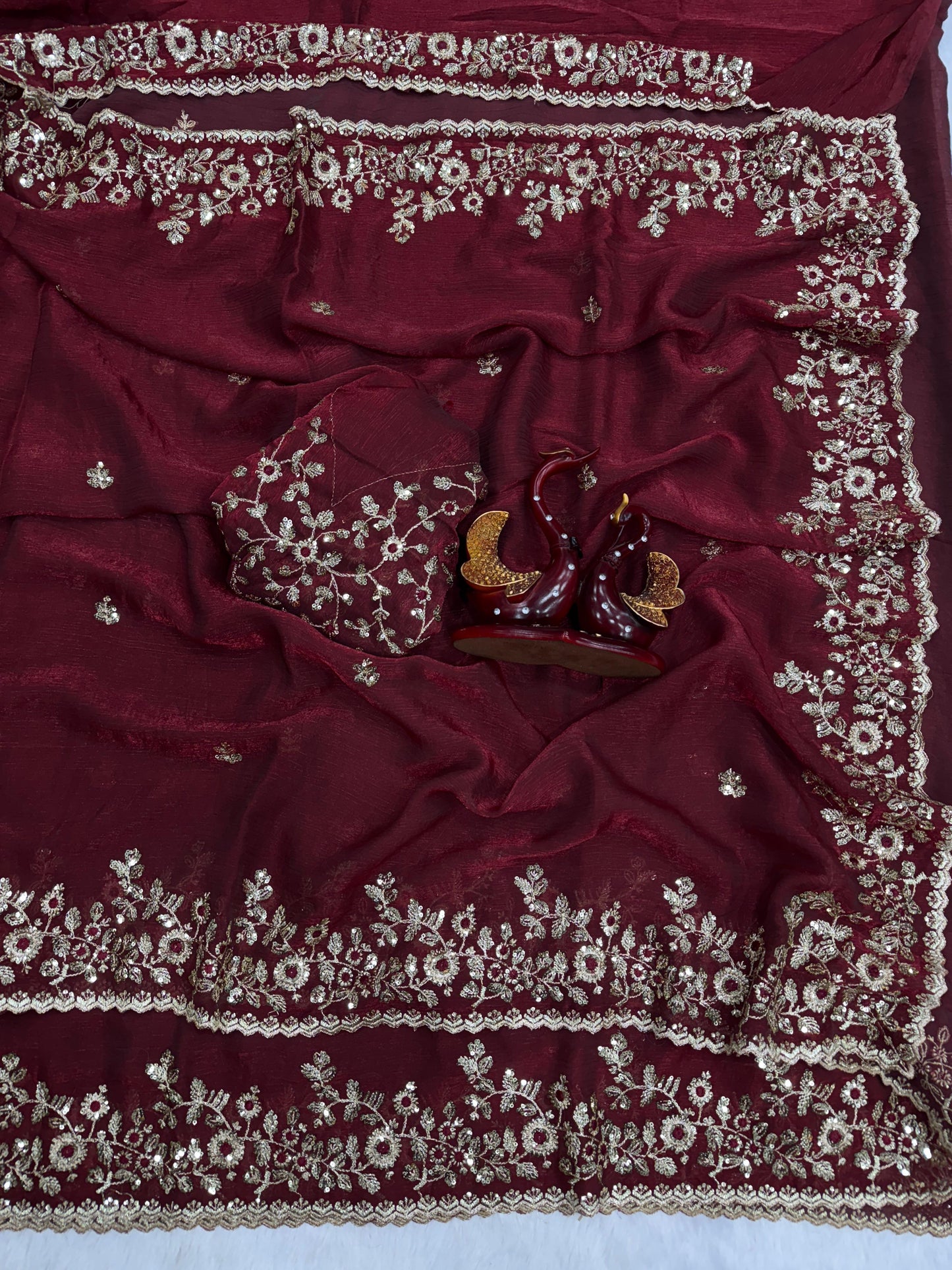 A royal maroon Fandy silk saree embellished with intricate silver floral embroidery across the pallu and border. The saree comes with a matching embroidered blouse, offering a regal and graceful traditional look ideal for festive and wedding occasions.