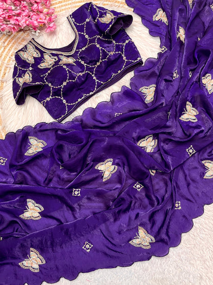 A royal purple space silk saree featuring detailed sequin butterfly embroidery and wavy scalloped edges. The ensemble comes with a matching embroidered blouse, creating a graceful and festive look.