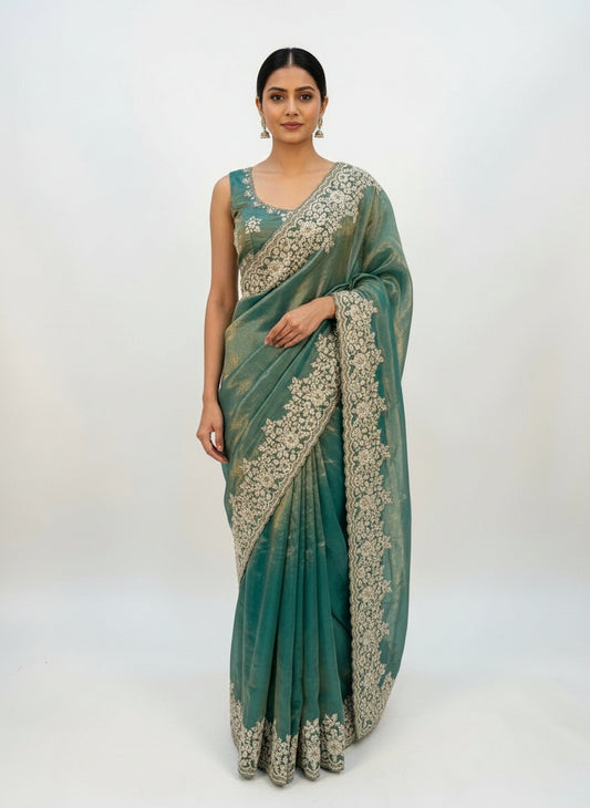 A soft sky blue Fandy silk saree adorned with intricate white floral embroidery along the border. The saree is paired with a matching embroidered blouse featuring coordinating floral motifs, creating an elegant and festive ethnic ensemble.