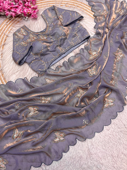 A smoky grey space silk saree decorated with delicate butterfly sequin motifs and wavy scalloped borders. The ensemble includes a matching stitched blouse with complementing embroidery, giving it a modern and elegant charm.