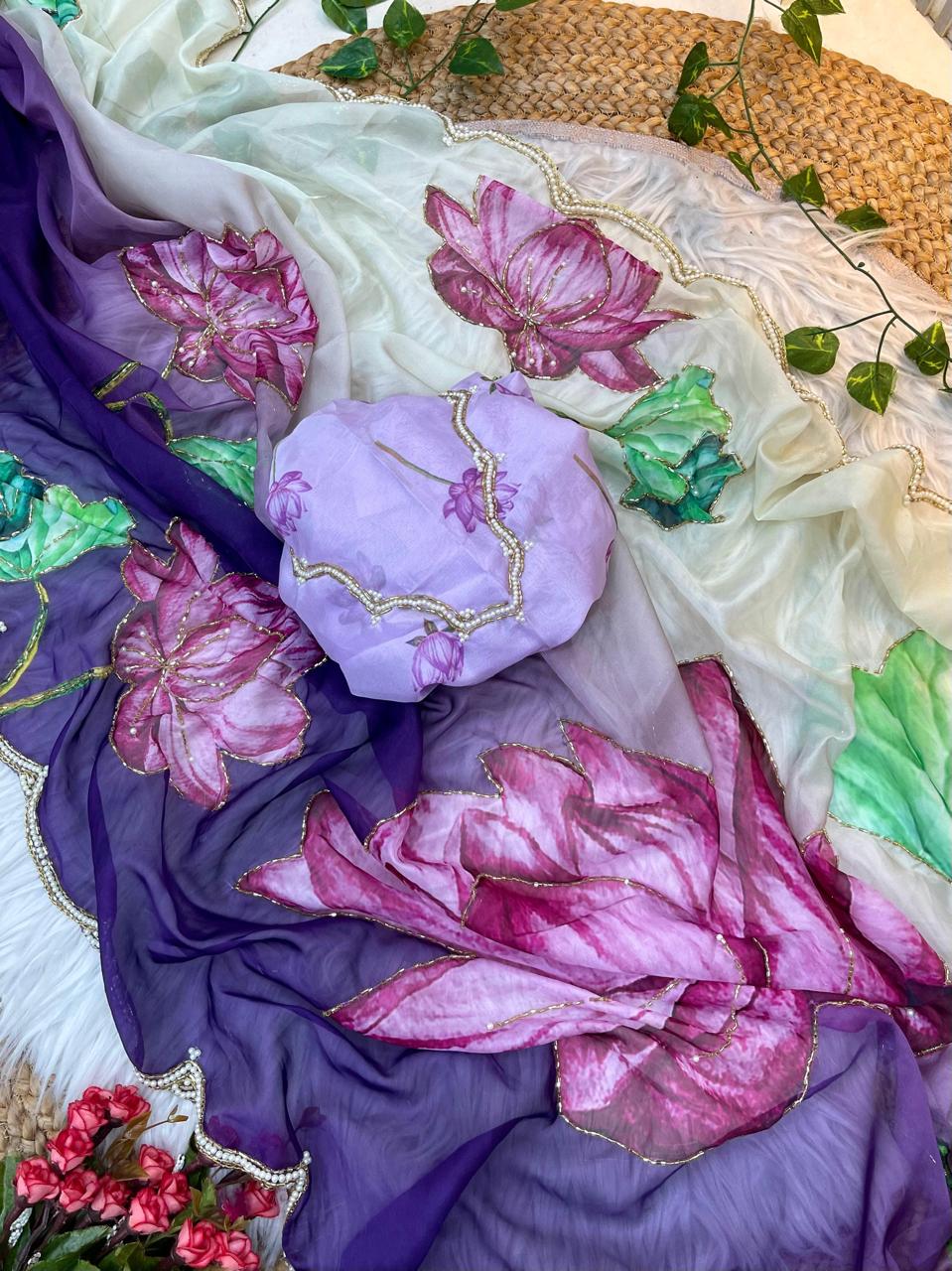 A festive soft organza saree showcasing large multicolor lotus artwork across the drape. The pearl scalloped lace border and coordinating blouse add charm and elegance, perfect for special occasions.
