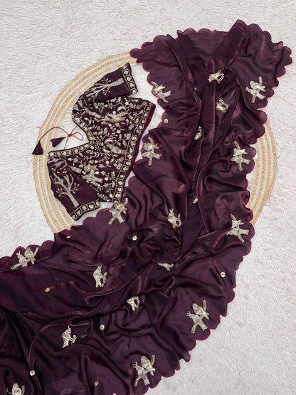 A wine-maroon space silk saree embellished with golden bird motifs and delicate scalloped edges. The coordinating embroidered blouse enhances the saree’s regal and timeless charm, perfect for festive and ceremonial wear.