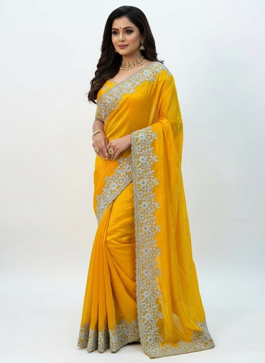 A bright yellow Fandy silk saree featuring intricate white floral embroidery along the border. The saree includes a matching embroidered blouse adorned with delicate white thread and bead motifs, creating a festive and elegant traditional look.